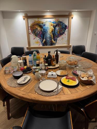 a table with food and a painting of an elephant at Chambre privée avec salle de bain in Domagné