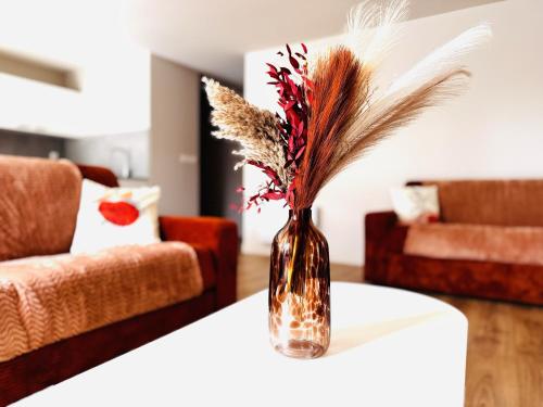 a vase with feathers on a table in a living room at Le Terracotta cocon moderne à 2 pas de la Gare ligne directe GENÈVE-LYON-PARIS in Bellegarde-sur-Valserine