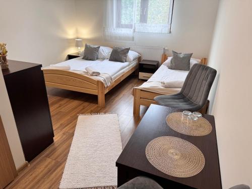 a room with two beds and a chair and a table at Willa Wioletta in Tylmanowa