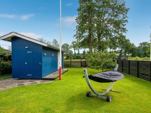 a chair sitting in the grass next to a blue shed at Holiday Home Urda - 50m from the sea by Interhome in Binderup Strand