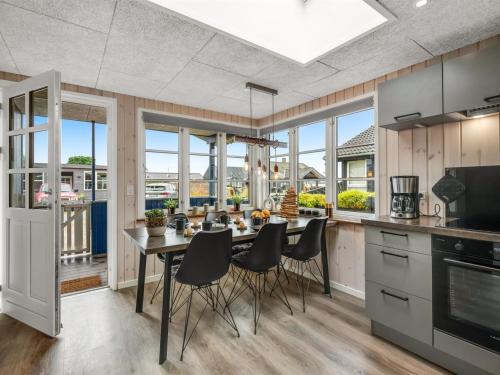 a kitchen with a table and chairs and windows at Holiday Home Urda - 50m from the sea by Interhome in Binderup Strand