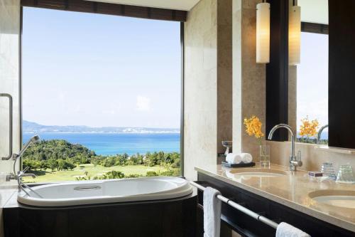 a bathroom with a tub and a view of the ocean at The Ritz-Carlton Okinawa in Nago