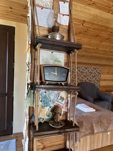 a clock on a swing in a room with a bed at Hotel Nestt in Stepantsminda