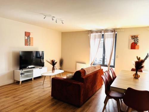 a living room with a couch and a tv and a table at Le Terracotta cocon moderne à 2 pas de la Gare ligne directe GENÈVE-LYON-PARIS in Bellegarde-sur-Valserine