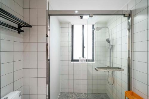 a white tiled bathroom with a shower and a window at Book and Bed-People's Square in Shanghai