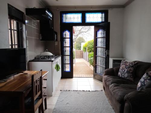 ヨハネスブルグにあるCharming Studio Oasis in Kensington, Johannesburgのリビングルーム(ソファ付)、オープンドア