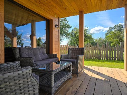 a porch with a couch and chairs on a deck at Okoń in Sztabin