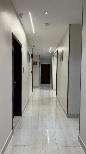 a hallway with white walls and a hallway with black doors at AN Studios in Al Khobar