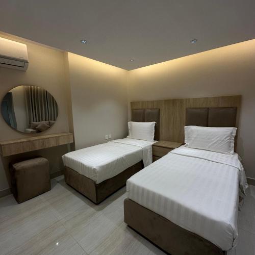 a hotel room with two beds and a mirror at AN Studios in Al Khobar