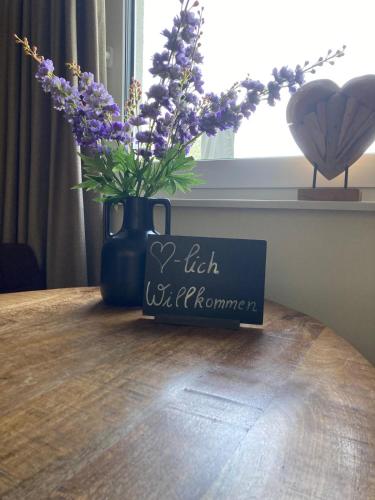 a sign on a table with a vase with purple flowers at Appartements Bergliebe in Bichlbach