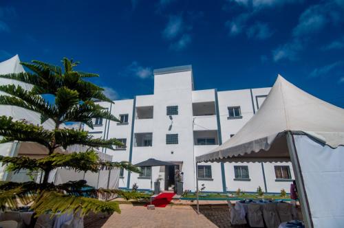 un bâtiment blanc avec un palmier devant dans l'établissement Résidence la Rivière Ambohijanahary, à Abohijanahary