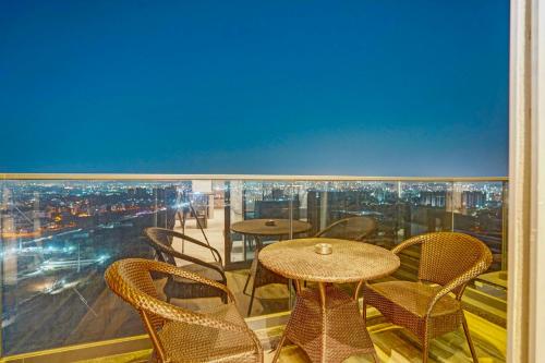 a balcony with tables and chairs and a view of a city at Sunday Hotel & Residences Gurugram in Gurgaon