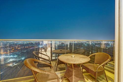 a balcony with tables and chairs and a view of a city at Sunday Hotel & Residences Gurugram in Gurgaon