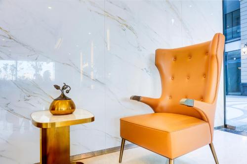 a orange chair next to a table and a vase at Sunday Hotel & Residences Gurugram in Gurgaon