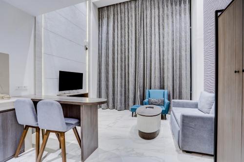 a living room with a television and a couch and a chair at Sunday Hotel & Residences Gurugram in Gurgaon