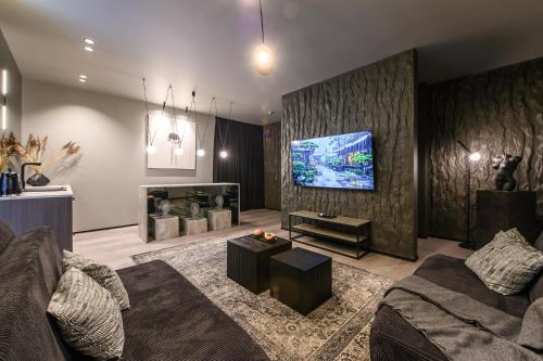 a living room with a couch and a flat screen tv at Jacuzzi Cinema Shibui 5 in Kaunas