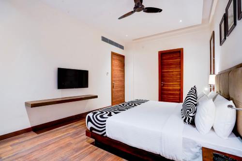 a bedroom with a bed and a tv on a wall at Sunday Resort & Spa Manesar Gurugram in Gurgaon