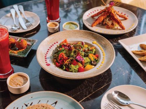 a table topped with plates of food and a bowl of salad at Sunday Resort & Spa Manesar Gurugram in Gurgaon