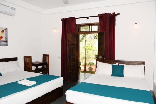 una camera da letto con due letti e una finestra di Leaf Dew Resort a Anuradhapura