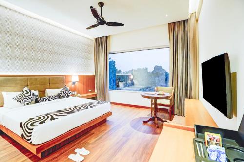 a hotel room with a bed and a large window at Sunday Resort & Spa Manesar Gurugram in Gurgaon