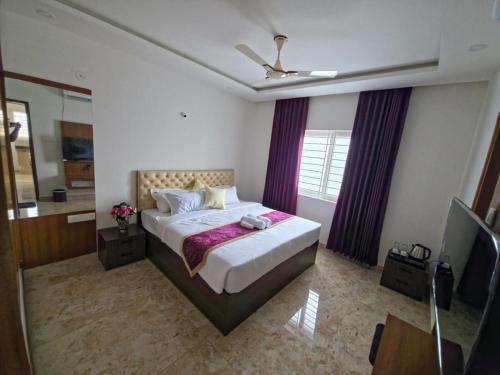 a bedroom with a large bed with purple curtains at Broadway Inn in Mysore