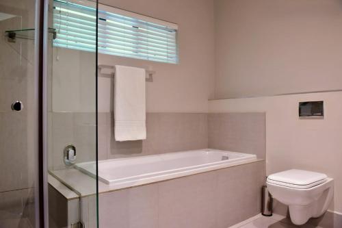 a bathroom with a bath tub and a toilet at Mint Hotel Rosebank in Johannesburg