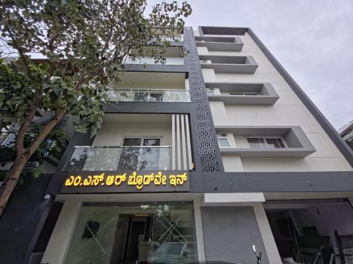 a tall white building with a sign on it at Broadway Inn in Mysore