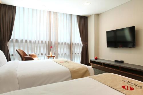 a hotel room with two beds and a flat screen tv at Hotel Skypark Kingstown Dongdaemun in Seoul