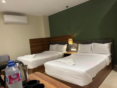 two beds in a room with a green wall at NOMAD PYRAMIDS AND SPHINX Hotel in Cairo
