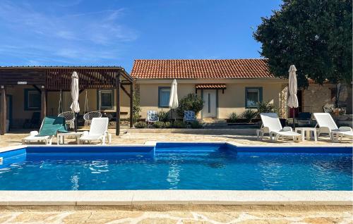 a pool with chairs and umbrellas next to a house at Nice Home In Benkovac in Benkovac