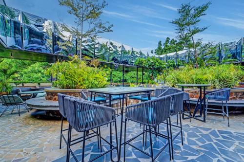 a patio with tables and chairs in a garden at HOTEL THE SLATE Near APOLLO HOSPITAL & US EMBASSY in Chennai
