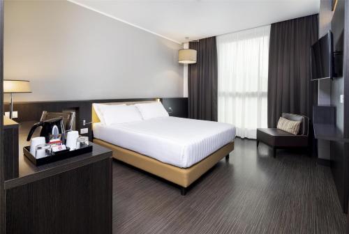a bedroom with a bed and a desk and a television at Best Western Premier CHC Airport in Genova