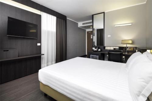 a bedroom with a large white bed and a desk at Best Western Premier CHC Airport in Genova