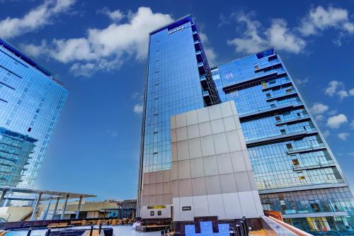a tall glass building with two tall buildings at Sunday Hotel & Residences Gurugram in Gurgaon