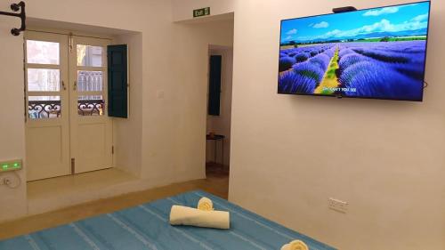 a living room with a flat screen tv on a wall at Vincenti's Rest in Birgu - a traditional old house in Birgu