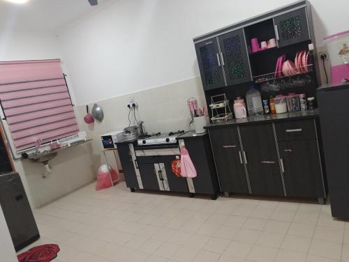 a kitchen with black cabinets and a stove top oven at FMS Homestay in Changlun