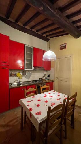 a kitchen with red cabinets and a table with a table cloth at Casa Le Campane sulla Via Francigena in Gambassi Terme