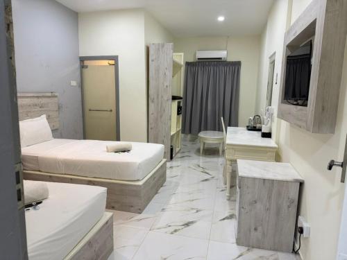 a room with two beds and a table and a room with at Paradise Resort Langkawi in Pantai Cenang