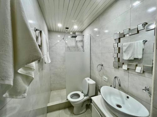 a white bathroom with a toilet and a sink at Campus Luxe Castle Hotel in Yerevan