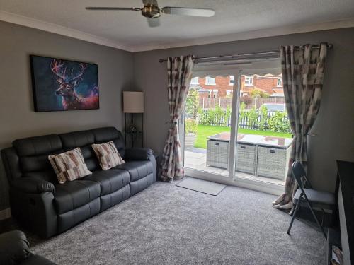 a living room with a couch and a sliding glass door at The Meadows in Market Drayton
