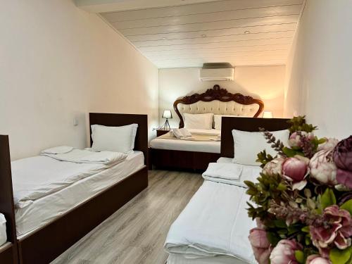 two beds in a hotel room with flowers at Campus Luxe Castle Hotel in Yerevan