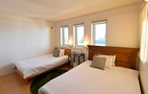 two beds in a room with two windows at Maccha House Near Zenkoji Nagano in Nagano