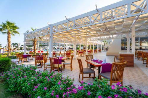 an outdoor patio with tables and chairs and flowers at Seven Seas Jolie Bay - Ultra All Inclusive in Hurghada