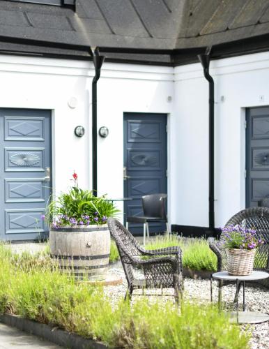 two chairs and a table in front of a house with blue doors at Kåseberga Gårdshotell & Spa in Kåseberga