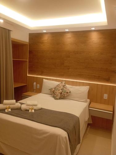 a bedroom with a large bed with a wooden headboard at Hotel Pousada Casacolina in Búzios