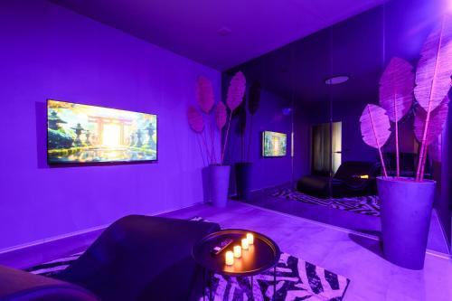 a purple room with a couch and a table with candles at Jacuzzi Cinema Japandi 2 in Kaunas