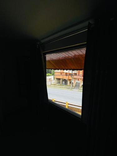 a window in a dark room looking out at a street at Hotel Garnier in Campos do Jordão