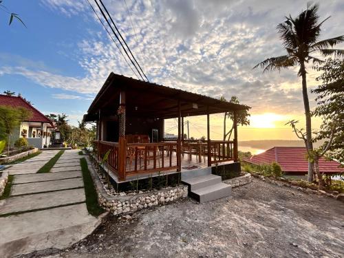 a small building with a porch and a palm tree at Gamat Sunset Cottage and Resto in Nusa Penida