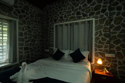 a bedroom with a bed with pillows and a window at Villa La Vista Homestay in Calicut