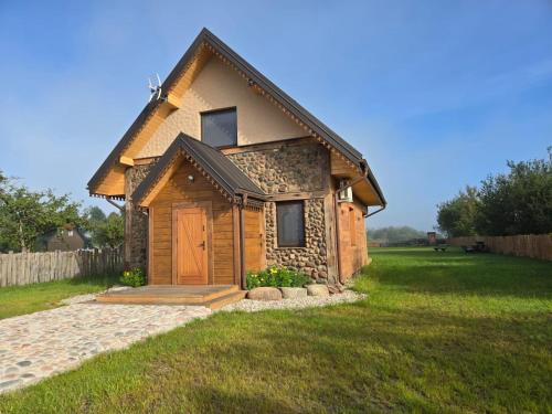 a small log cabin with a door in a yard at Okoń in Sztabin